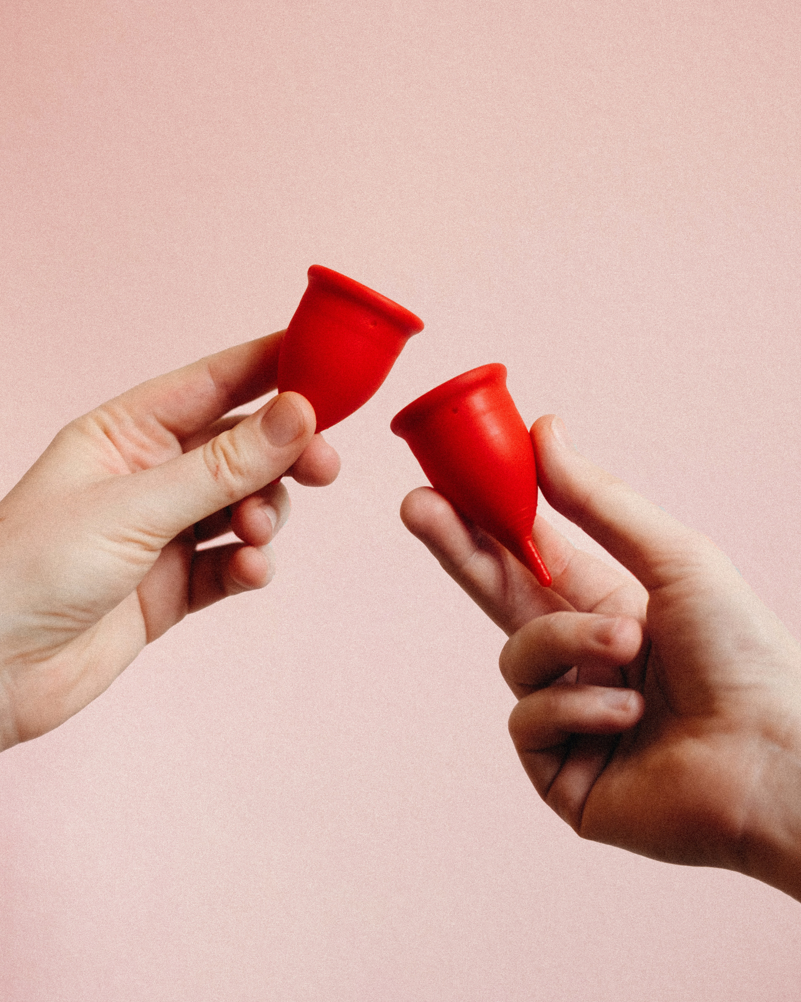 Best period products for PCOS: hands holding unused red menstrual cups