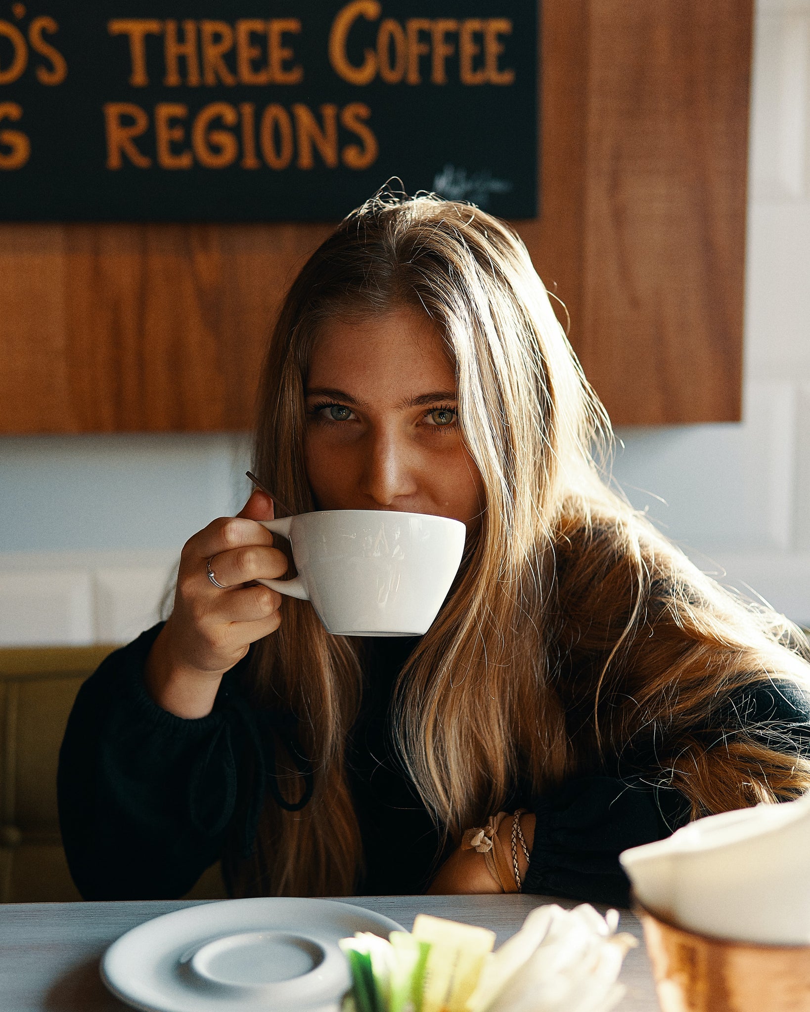 PCOS and caffeine – woman drinking cappuccino from mug and looking at camera