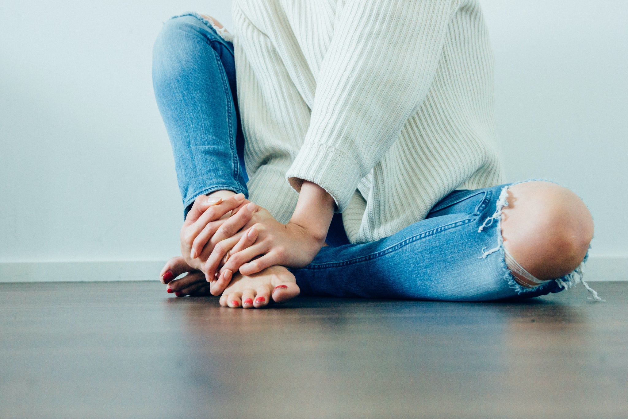 PCOS diagnosis: person sat on floor holding foot in hands