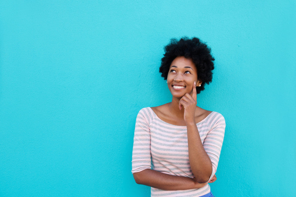 Woman thinking about PCOS against a blue wall